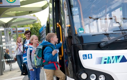 Schulkinder steigen in Bus ein